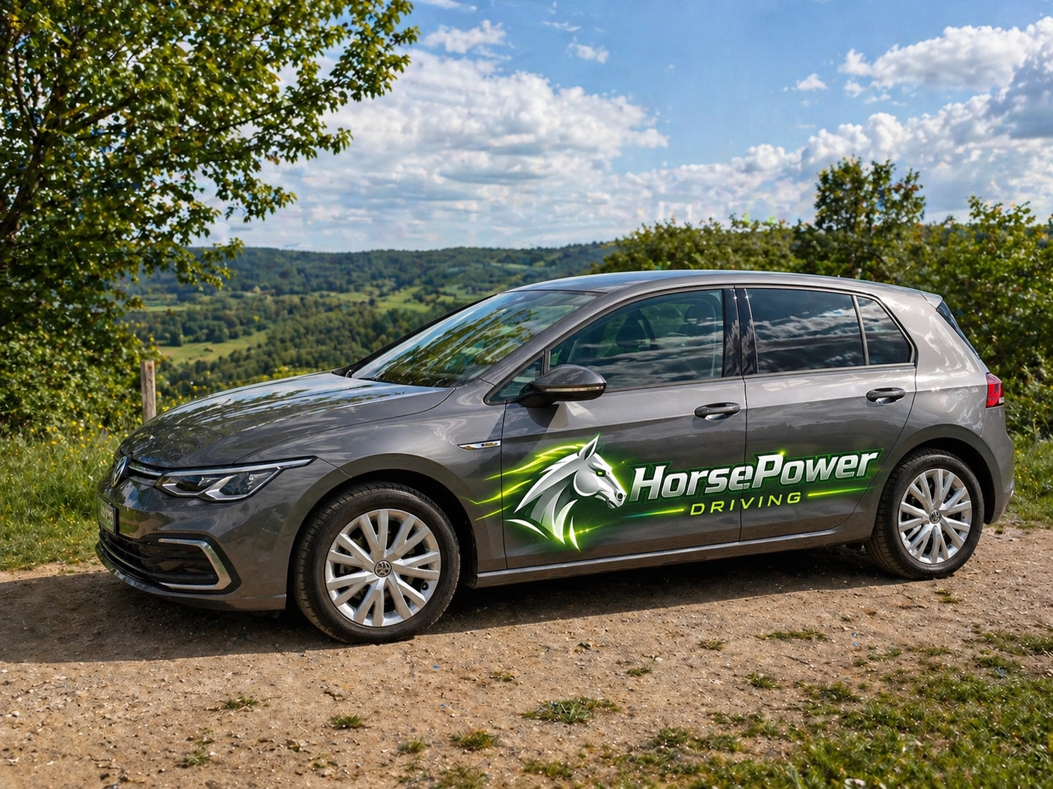 Horsepower Driving - Fahrschule - Ein grauer VW Golf Schrägheckwagen steht am Rand eines Feldwegs. Im Hintergrund erheben sich sanfte grüne Hügel.